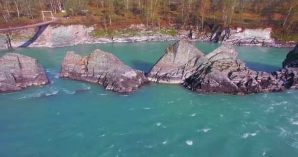 Vol à basse altitude au-dessus d'une rivière de montagne fraîche et rapide avec des rochers au soleil matin d'été. — Video