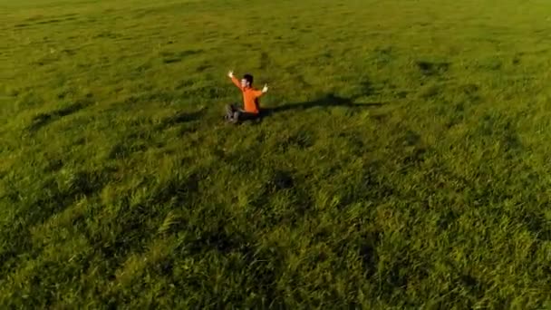 Vuelo radial de baja altitud sobre el hombre del yoga del deporte en hierba verde perfecta. Puesta de sol en montaña. — Vídeos de Stock