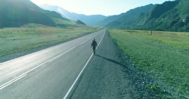 히치 하이킹을 하는 관광객 이 아스팔트 길을 걷는 모습. 여름철에는 거대 한 시골 계곡이 펼쳐져 있다. 배낭 여행자. — 비디오