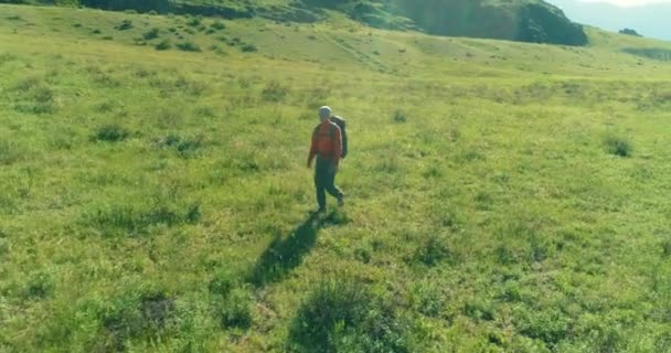 Vol au-dessus du sac à dos randonnée touristique marche à travers le champ de montagne vert. Vallée rurale énorme au jour d'été. — Video