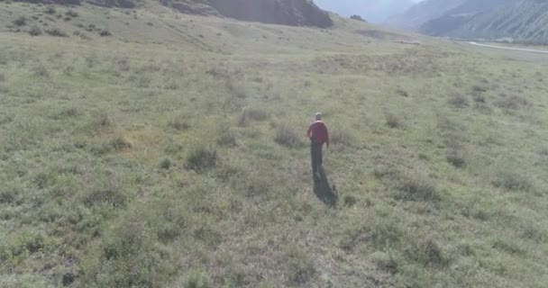 Terbang di atas Backpack hiking turis berjalan melintasi lapangan gunung hijau. Besar lembah pedesaan pada hari musim panas. — Stok Video