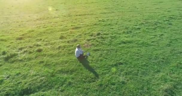 Lage baanvlucht rond mens op groen gras met notitieblok op geel landelijk veld. — Stockvideo