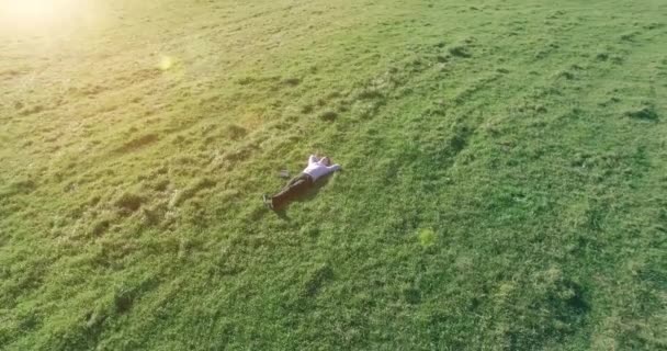 Lage baanvlucht rond mens op groen gras met notitieblok op geel landelijk veld. — Stockvideo