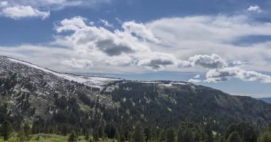 Dağların arkasındaki bulutların zaman çizelgesi. Kar, kayalar, uçurumlar ve derin mavi gökyüzü. Yüksek irtifa.