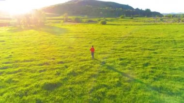 Mükemmel yeşil çayır üzerinde uçan bir sporcu. Dağda gün batımı
