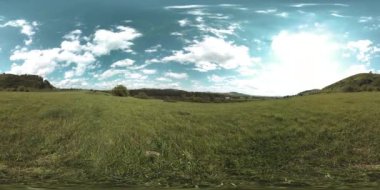 360 VR 'lık güzel bir dağ çayırı zaman dilimi. Yaz ya da sonbahar zamanında. Bulutlar, yeşil çimenler ve güneş ışınları.
