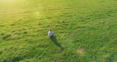 Yeşil çimlerin üzerinde sarı kırsal alanda not defteri olan bir adamın etrafında alçak yörünge uçuşları..