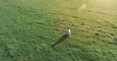 Yeşil çimlerin üzerinde sarı kırsal alanda not defteri olan bir adamın etrafında alçak yörünge uçuşları..