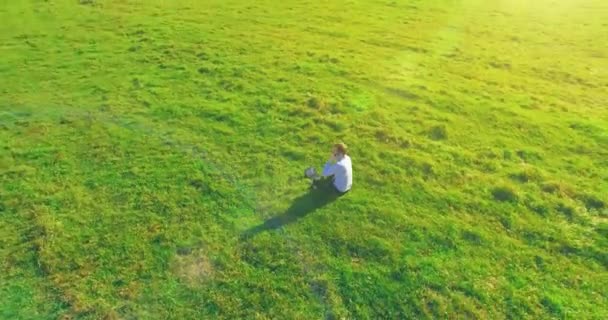 Basso volo orbitale intorno all'uomo su erba verde con blocco note al campo rurale giallo. — Video Stock