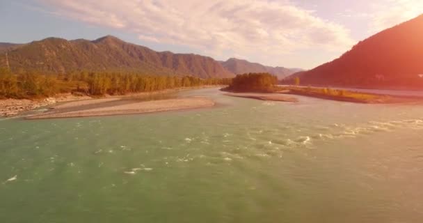 4k UHD航空ビュー。晴れた夏の朝に新鮮な冷たい山の川の上に低飛行。地平線の緑の木と太陽の光 — ストック動画