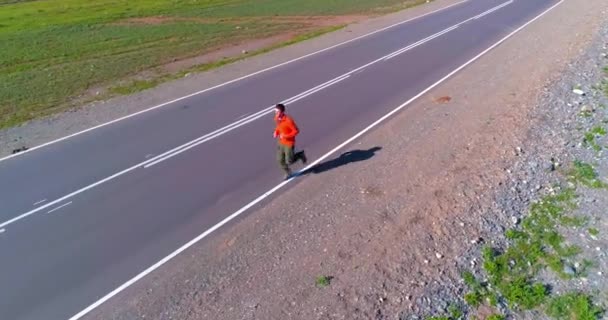 Voo de baixa altitude na frente do homem desportivo na estrada de asfalto perfeito — Vídeo de Stock