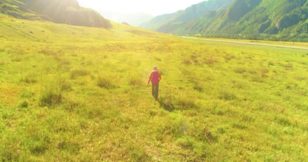 Let nad batohem turistické procházky přes zelené horské pole. Obrovské venkovské údolí v letní den. — Stock video