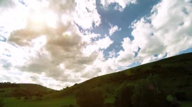 Yazın 4K UHD dağ çayırı zaman dilimi. Bulutlar, ağaçlar, yeşil çimenler ve güneş ışınları hareketi.