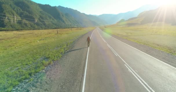 Vlucht over lifter toerist wandelen op asfalt weg. Enorme landelijke vallei op zomerdag. Rugzakwandelaar. — Stockvideo