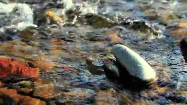 Dolly-Slider-Aufnahme des plätschernden Wassers in einem Gebirgsfluss in Waldnähe. Nasse Felsen und Sonnenstrahlen. Horizontale stetige Bewegung. — Stockvideo