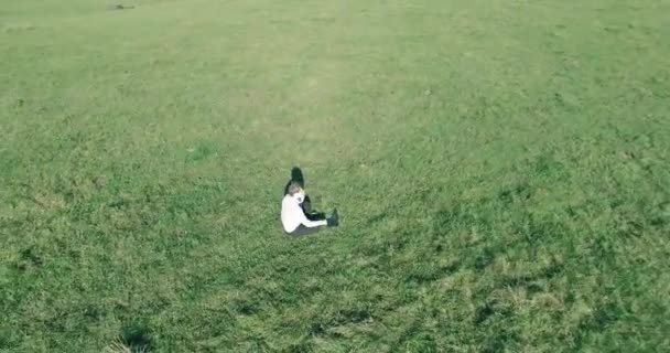 Vol orbital bas autour de l'homme sur herbe verte avec bloc-notes au champ rural jaune. — Video