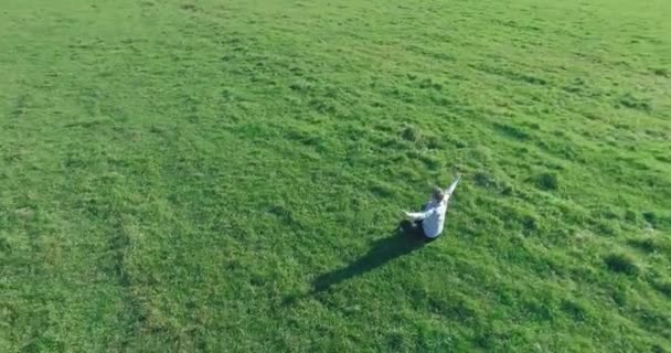 Basso volo orbitale intorno all'uomo su erba verde con blocco note al campo rurale giallo. — Video Stock