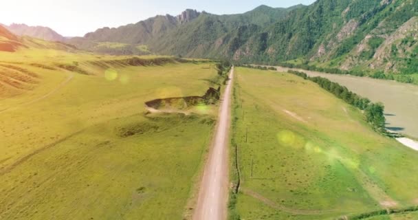 Luftlinie ländliche Bergstraße und Wiese an einem sonnigen Sommermorgen. Asphaltstraße und Fluss. — Stockvideo