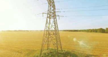 Yüksek voltajlı elektrik kulesi ve yeşil ve sarı alandaki elektrik hatları yakınında dikey hareket.