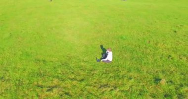 Yeşil çimlerin üzerinde sarı kırsal alanda not defteri olan bir adamın etrafında alçak yörünge uçuşları..