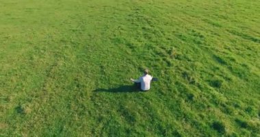 Yeşil çimlerin üzerinde sarı kırsal alanda not defteri olan bir adamın etrafında alçak yörünge uçuşları..