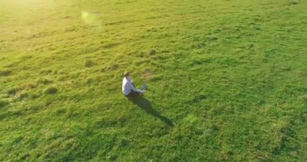 Lage baanvlucht rond mens op groen gras met notitieblok op geel landelijk veld. — Stockvideo