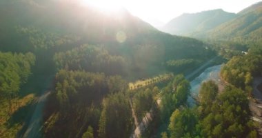 Güneşli yaz sabahında taze dağ nehri ve çayır üzerinde uçuşun ortasında. Aşağıdaki kırsal toprak yol.
