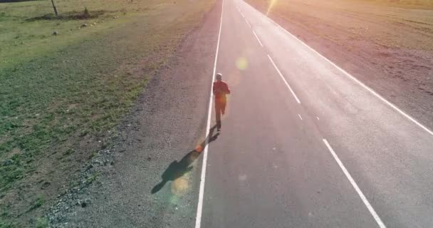 Vuelo de baja altitud frente al deportista en el camino perfecto de asfalto — Vídeos de Stock