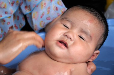 Bozuk bir ifadeyle mavi bir havuzda banyo yaparken yakalanan bir çocuk.