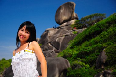 Similan Adaları 'ndaki bir yelkenliye benzeyen kayalık bir arka planda poz veren genç kadınlar Tayland' ın ünlü turistik merkezleri..