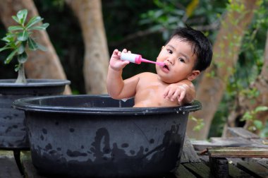 Beyaz çocuk siyah havzalarda oturmuş, dişlerini fırçalıyor..