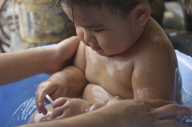 Küçük çocuk mavi havzada suyun içinde oturuyordu, yakın plan bir görüntü mü?.
