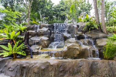 Yapay şelale ve bahçede heykel.