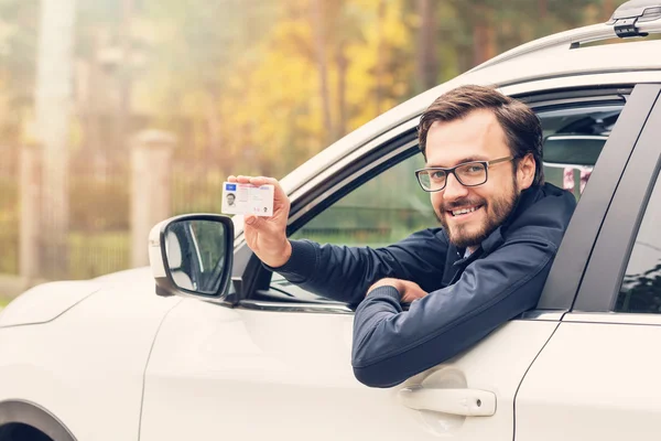 Man in de auto zit en zijn rijbewijs tonen — Stockfoto