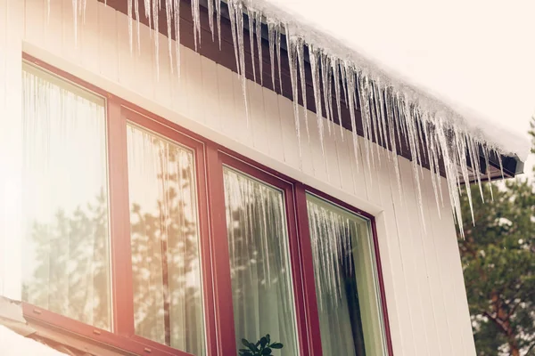 Warmteverlies - ijspegels opknoping op het dak van het huis — Stockfoto