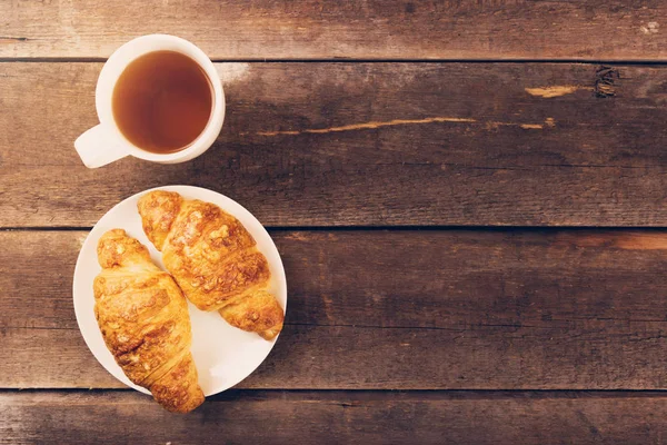 Croissant with cup of tea on wooden table. copy space — Stock Photo, Image