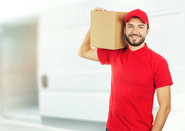 Счастливый доставщик с коробкой на плече перед грузовиком — стоковое фото