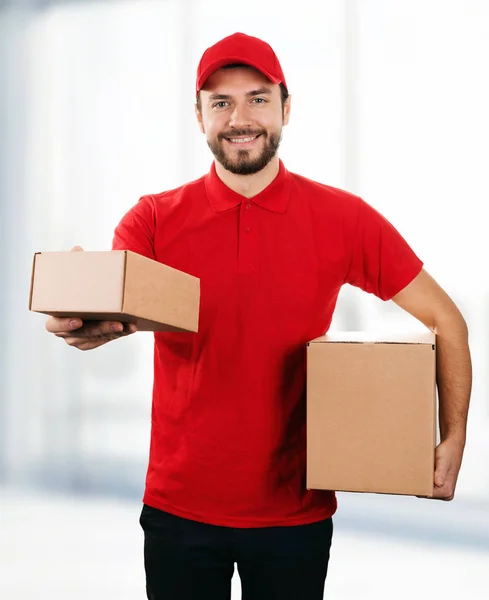 Servizio di consegna - giovane fattorino sorridente con scatola di cartone — Foto Stock
