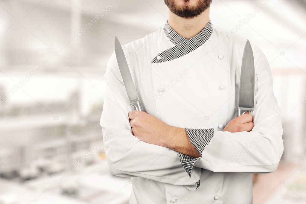 chef standing in the restaurant kitchen with knives in hands