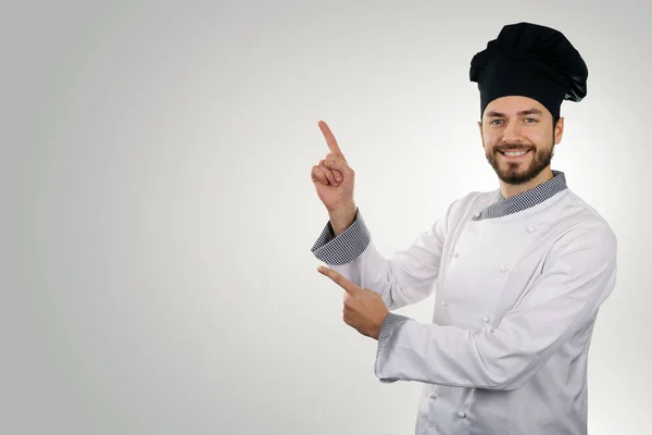 Young happy chef pointing on copy space — Stock Photo, Image