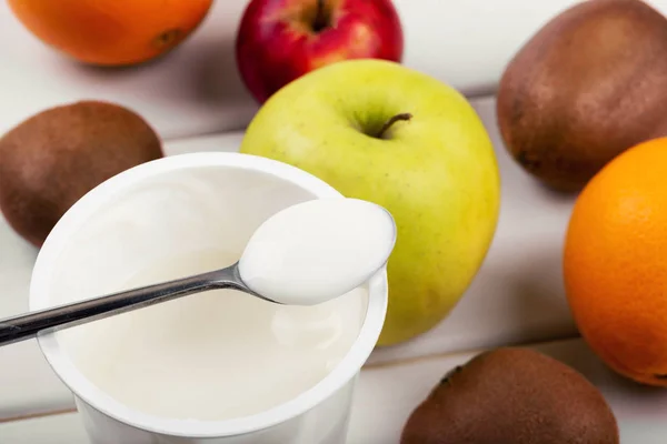 Spoon with yogurt and fruits on white wooden table — Stock Photo, Image