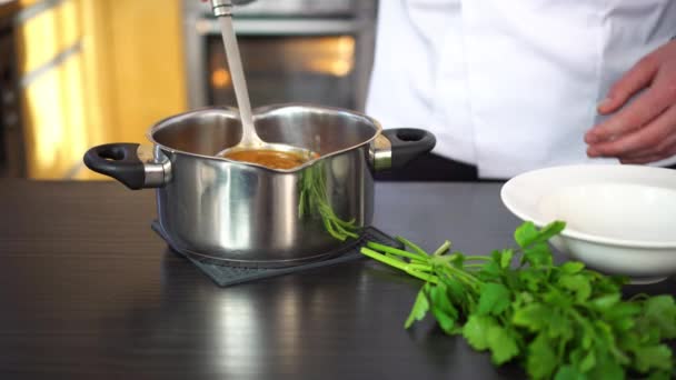 Σεφ χύνοντας σούπα σε ένα πιάτο και διακοσμεί με βότανα — Αρχείο Βίντεο
