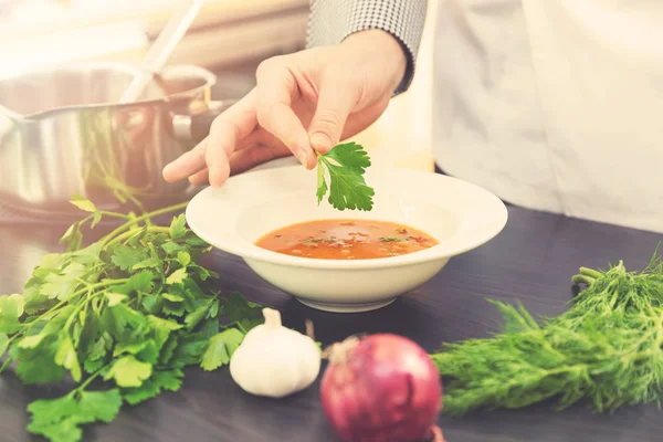 Kocken dekorera soppa med örter i köket — Stockfoto