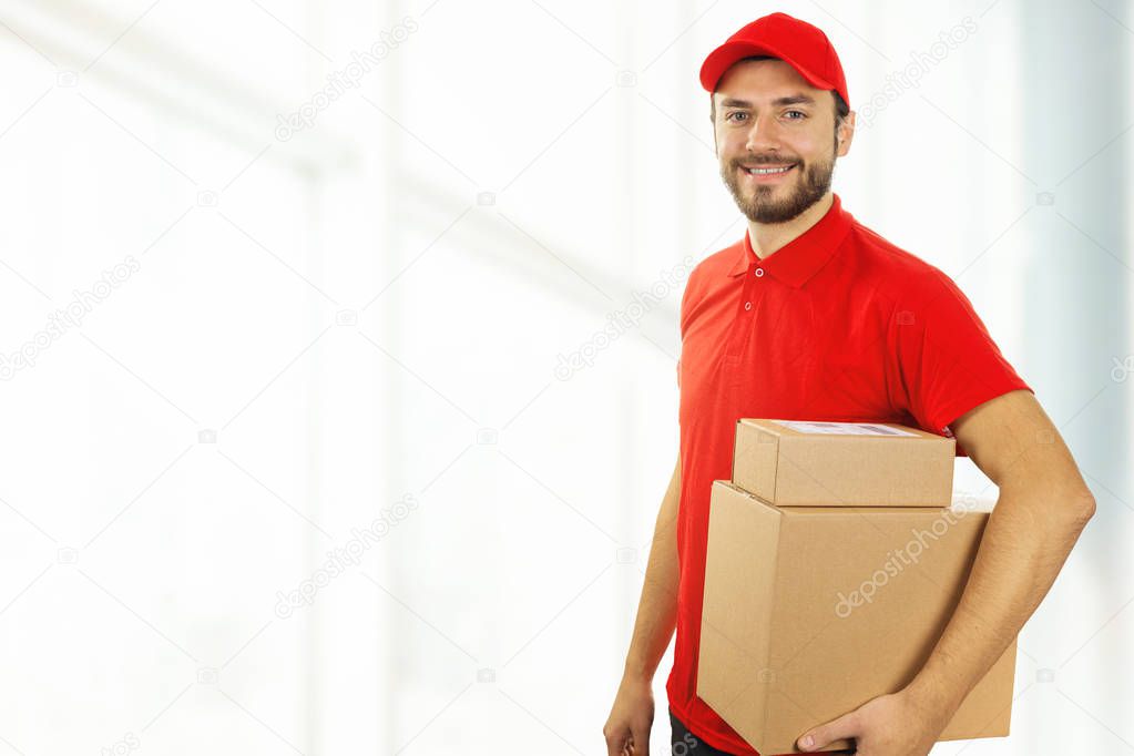 delivery man with cardboard boxes standing in office. copy space