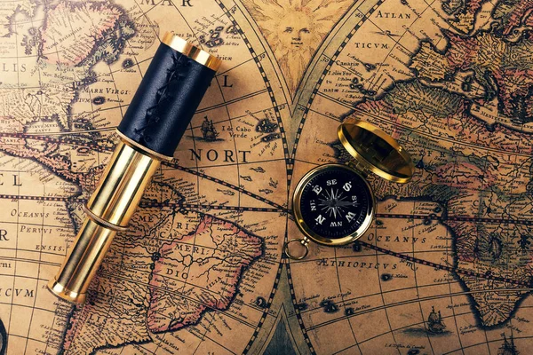 Vintage compass and spyglass on ancient world map — Stock Photo, Image