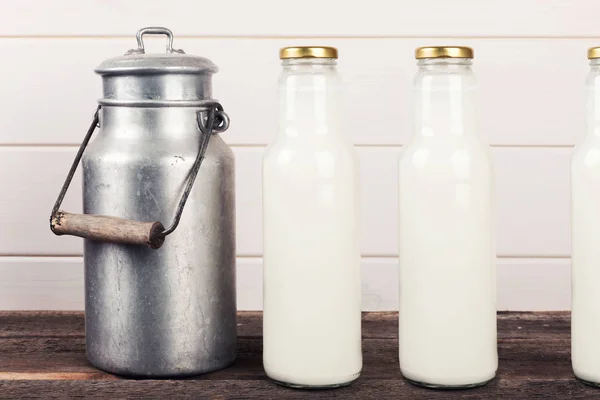 Lata de leche vieja y botellas en mesa de madera — Foto de Stock