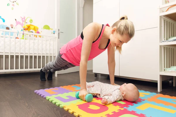 Mãe fazendo fitness e brincando com seu bebê — Fotografia de Stock