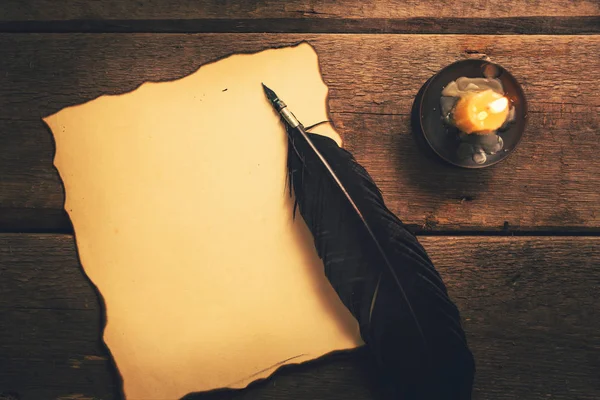 Pluma vintage y papel viejo en blanco a la luz de las velas sobre la mesa — Foto de Stock