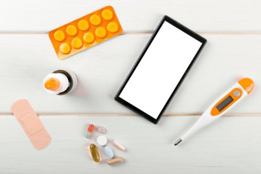Masanın üzerindeki tıbbi öğelerle boş smartphone. Üstten Görünüm