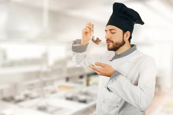 Ποιοτικός έλεγχος - chef δοκιμάζοντας σούπα από την κουτάλα στην κουζίνα — Φωτογραφία Αρχείου